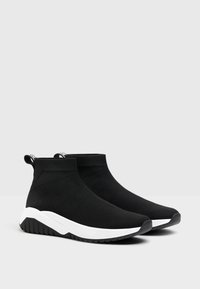 Sneakers neri in maglia con design a caviglia alta, dotati di suola bianca e tomaia testurizzata, completati da una maniglia per facilitare l'uso.