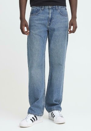 Ljusblå denimjeans med avslappnad passform, rak bendesign, femficksstil och subtila blekningar. I kombination med vita sneakers.