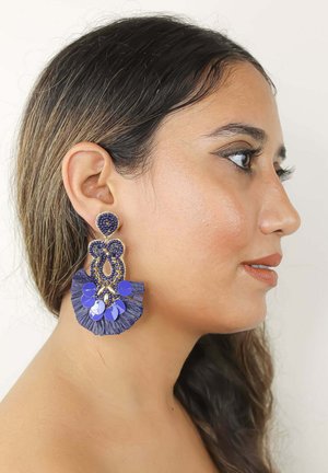 Boucles d'oreilles en bleu avec des franges, comportant un travail de perles complexe et des accents brillants, alliant différentes textures et formes pour un intérêt visuel.