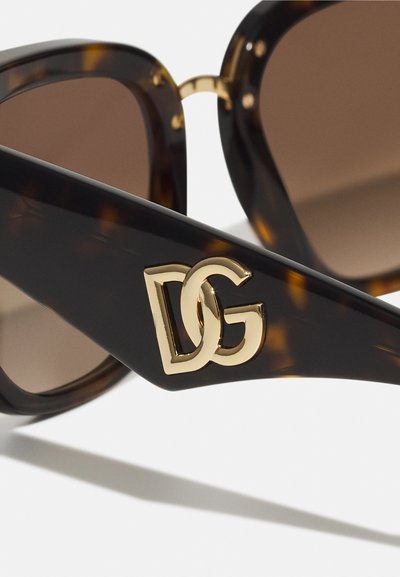 Ochelari de soare țestoasă cu lentile maro gradient, având un cadru acoperit negru îndrăzneț din acetat și un logo aurie "DG" pe tâmplă.