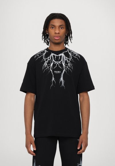 T-shirt in cotone nero con una grafica di un fulmine bianco sulla parte anteriore e il testo "PHOBIA" centrato sotto il design. Maniche corte.