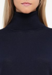 Navy turtleneck sweater in ribbed texture. Fitted design with a high collar and smooth finish. Seam details at the shoulders for added structure.