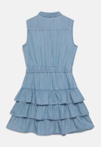 Vaaleansininen farkkukangasinen hihaton mekko, jossa kaulus, vyötärömyötäinen leikkaus ja kerroksittainen röyhelöhame. Pehmeä koostumus, jossa näkyvät ompelusaumojen yksityiskohdat.