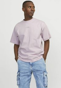 Ljuslila bomulls t-shirt med rund hals och korta ärmar, med en liten grafik i mitten. Bärs med ljusblå cargojoggers.