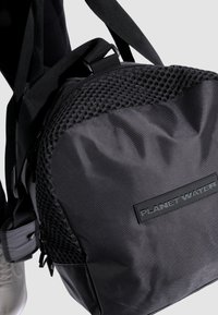 Mochila negra de nylon texturizado, con parte superior de malla, correas ajustables y un parche de marca que dice "PLANET WATER."