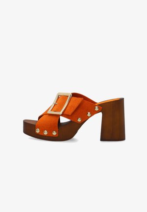 Sandale à talon haut orange avec talon bloc en bois, boucle dorée sur les brides croisées et détails de clous dorés le long des bords.