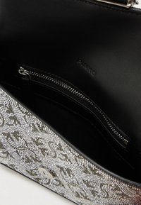 Μαύρη δερμάτινη τσάντα χειρός με ασημένια ζωγραφισμένη εξωτερική επιφάνεια και μαγνητικό κλείσιμο. Το εσωτερικό διαθέτει μια τσέπη με φερμουάρ και ανάγλυφο λογότυπο.