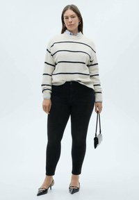 Textured cream sweater with navy stripes, paired with black skinny jeans. Pointed black flats and a small black handbag complete the look.