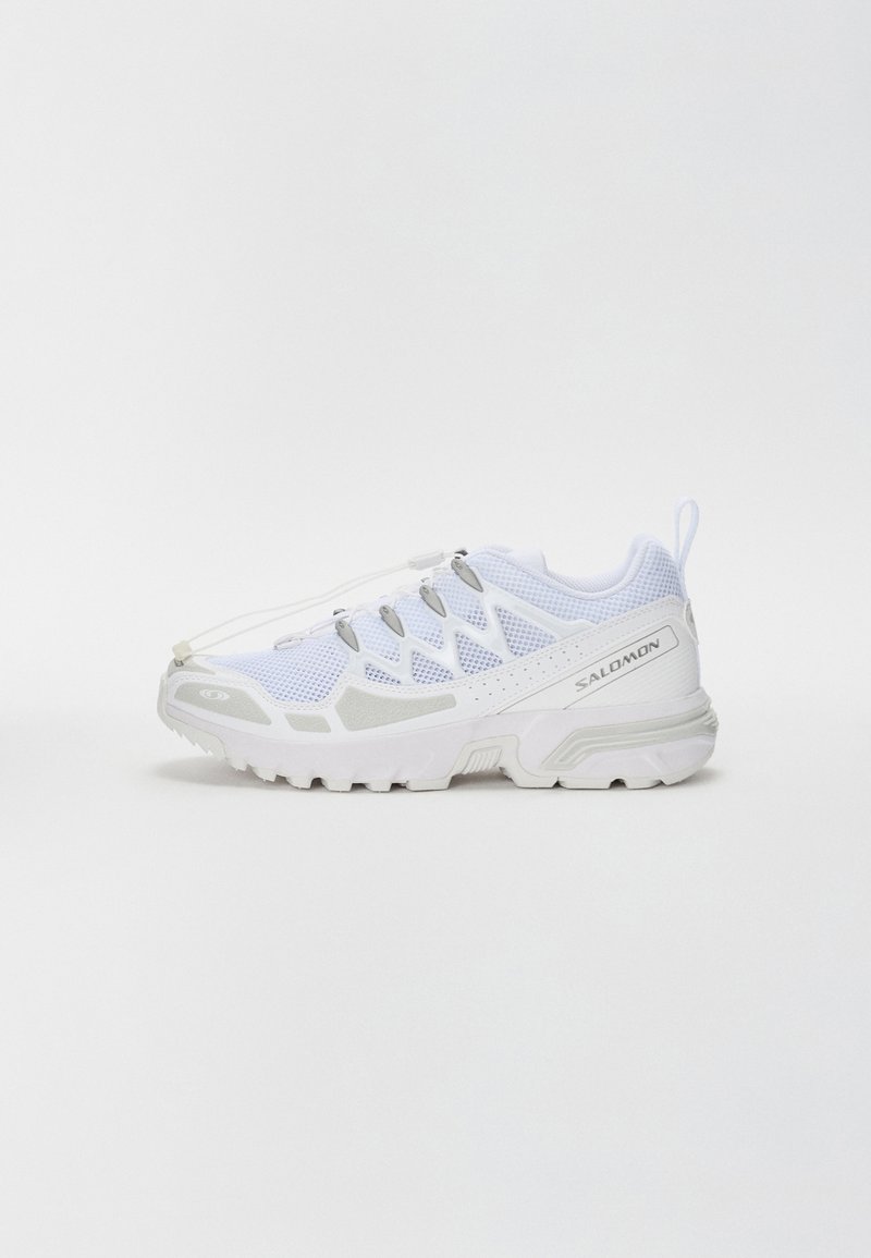 Valkoiset urheilukengät, joissa on verkkopinta, tekstuurisia yksityiskohtia ja harmaa kumipohja. Varustettu joustavilla nauhoilla ja vahvistetulla kärjellä.