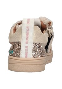 Sneaker met een beige suède bovenwerk, glinsterende roségouden achterkant, witte trekband met roze tekst en een gestructureerde beige rubberen zool.