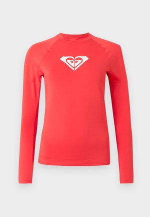 Jasnoczerwona, długorękawowa koszulka chroniąca przed otarciami z białym, stylizowanym logo serca na środku klatki piersiowej, na jednolitym jasnym tle.