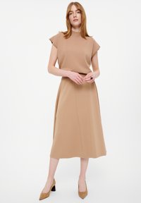 Beiges Kleid mit kurzen, strukturierten Ärmeln, einem hohen Halsauschnitt und einem fließenden A-Linien-Rock. Der Stoff hat eine glatte Textur.