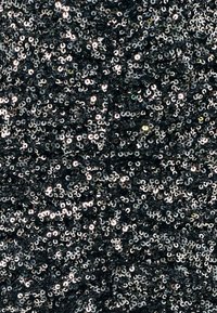 Črno blago gosto prekrito z bleščečimi črnimi in srebrnimi bleščicami, ki odbijajo svetlobo.