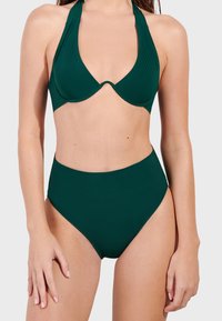 Zielony bikini składający się z topu na halter z głębokim dekoltem w kształcie V oraz wysokich majtek. Gładka tekstura, minimalistyczny design, bez widocznych wzorów.