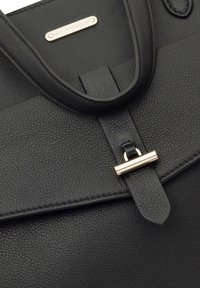 Sac à main en cuir noir avec une surface texturée, une fermeture à rabat et des accents en métal doré pour plus de détails.
