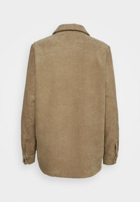 Brun kordflätad jacka med krage, lång ärm och knäppte manschetter. Har texturerad ribbning och en rak nederkant bak.