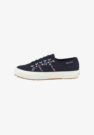Navy canvas sneaker with white rubber sole, featuring floral embroidery in pink and green. Includes six eyelets and a pink logo on the heel.