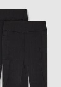 Czarne legginsy z gładkiego, elastycznego materiału. Posiadają szeroki pas i kieszonkę boczną, wyeksponowane na płasko, aby podkreślić detale i kształt.