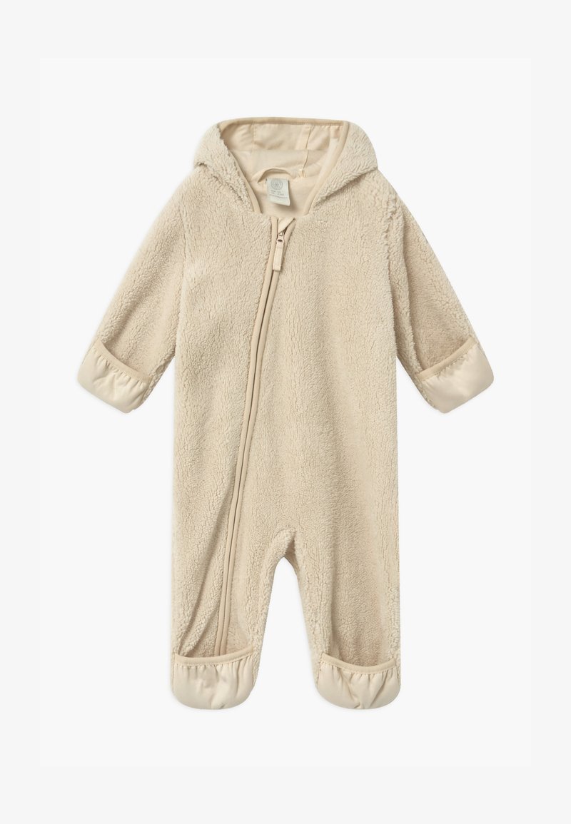Beige hette-jumpsuit laget av myk, teksturert stoff med glidelås. Har elastiske mansjetter ved ermer og føtter for tettsittende passform.