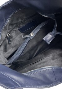 Granatowa skórzana torebka wewnątrz z czarną tkaniną, z wieloma kieszeniami na zamek i gładką fakturą. Widoczne detale zamków.