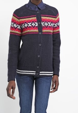 Strikket cardigan i mørkeblå med multi-farvet geometrisk design over brystet. Har knapper, ribbede ærmer og stribede kanter.