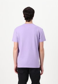 Lila Baumwoll-T-Shirt mit Rundhalsausschnitt, kurzen Ärmeln und geradem Saum; verfügt über eine subtile Textur und eine Rückennaht.