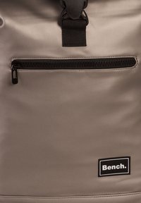 Grau wasserdichte Tasche mit einem zentralen Reißverschlussfach, verstellbarem Tragegurt und einem schwarzen Logo-Tag. Glatte Textur und strapazierfähiges Material.