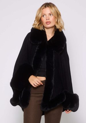 Cape noir avec des bordures en fausse fourrure au col et sur les bords, présentant une texture lisse. Le design est large et fluide, offrant une coupe décontractée.