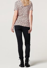 Fitted pink t-shirt with a black leopard print pattern, paired with black jeans and black lace-up boots. Back view of the outfit.