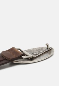Brown leather belt with a metal buckle showcasing a round shape, textured surface, and three circular accents on the top.