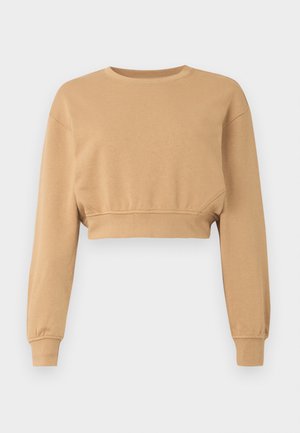 Kratka sneakerska majica v svetlo rjavi barvi, izdelana iz mehkega materiala. Ima dolge rokave, zaobljen izrez in subtilno elastiko na manšerah in robu.