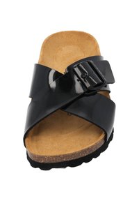 Schwarze patentierte Riemensandale mit über Kreuz verlaufenden Riemen, Kork-Innensohle und strukturiertem Gummiaußensohle. Verfügt über eine große verstellbare Schnalle.