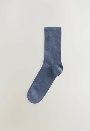 Calzino a coste blu navy realizzato in materiale morbido ed elastico, caratterizzato da una parte superiore senza cuciture e una punta rinforzata per una maggiore resistenza e comfort.