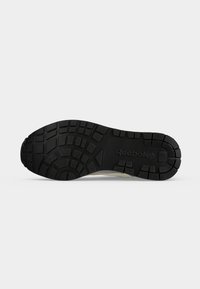 Μαύρη υφασμάτινη σόλα παπουτσιού Reebok με σχεδιασμένο πέλμα και το λογότυπο Reebok στο κέντρο, εμφανίζεται σε απλό φωτεινό φόντο.
