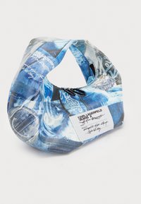Blue fabric bag with an abstract denim print and mixed graphics. Features a curved shape, top closure, and a label with black text.