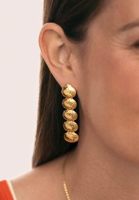 Goldfarbene hängende Ohrringe mit fünf strukturierten Muschelformen, die vertikal angeordnet sind, mit einer polierten Oberfläche und glatten Kanten.