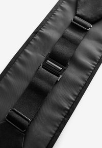 Black fabric strap with smooth texture, featuring adjustable black hardware and a buckle closure at the center. Minimalist design.