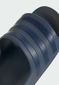 Sandalia de piscina azul marino con tres correas texturizadas y una plantilla texturizada. Fabricada en material sintético con un acabado suave.