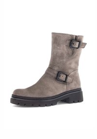 Stivaletto in suede taupe con due fibbie nere regolabili, punta tonda e suola in gomma nera spessa con profonde scanalature.