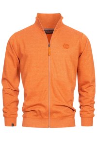 Veste zippée orange avec un col montant, en tissu texturé, et un petit logo sur la poitrine. Présente des poignets et un ourlet côtelés.