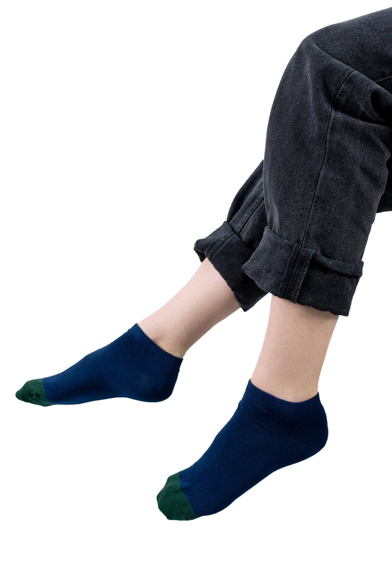 Granatowe skarpetki sięgające kostki z zielonymi akcentami na palcach, wykonane z lekkiego materiału, zaprezentowane na zwiniętych czarnych dżinsach.