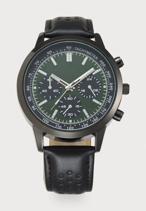 Fekete krónográf karóra zöld számlappal, ezüst kiegészítőkkel, tachiméter skálával és textúrázott fekete bőrszíjjával. Három alszámlap található rajta.