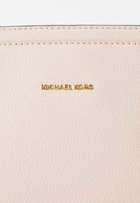 Roze leren portemonnee met textuur, met een gouden "MICHAEL KORS" logo. Gladde afwerking en minimalistisch ontwerp met strakke stikdetails.