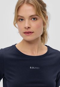Navyblauwe katoenen t-shirt met een ronde hals en korte mouwen. De voorkant heeft een zilveren logo-opdruk van "S.Oliver." Soepele textuur.