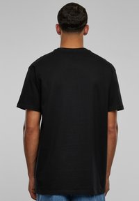 Sort bomulds t-shirt med korte ærmer, rund hals og en afslappet pasform, vist fra ryggen. Glat tekstur, uden synlige mønstre eller grafik.
