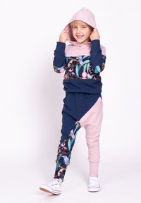 Kolorowy dres dziecięcy z różowym kapturem, kwiatowymi nadrukami na rękawach oraz granatowym tułowiem. Spodnie w jasnoróżowym i granatowym kolorze, o zwężanym kroju.
