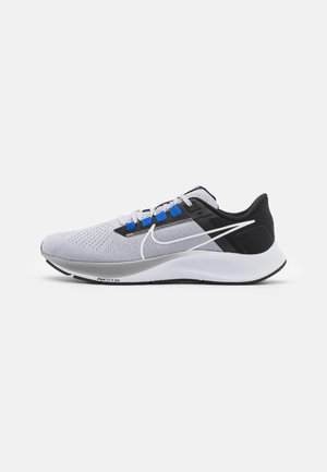 Zapatilla de correr gris claro y negra con suela blanca, ojales azules y logo Nike swoosh blanco en el lateral.