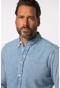 Camicia di denim azzurro chiaro con colletto a punta, bottoni frontali e un tessuto leggermente strutturato, caratterizzata da una vestibilità casual e maniche corte.