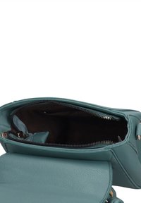 Borsa a mano in pelle turchese con esterno testurizzato, chiusura con zip e interno liscio. Presenta una piccola tasca e dettagli in metallo tono oro.