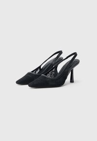 Μαύρα πέδιλα με λουράκι στην πλάτη, μυτερή μύτη, λεπτομέρειες με δαντέλα και επάνω μέρος από υφασμα με υφή. Διαθέτουν λεπτό τακούνι στιλέτο και μαύρο διακοσμητικό λουράκι.